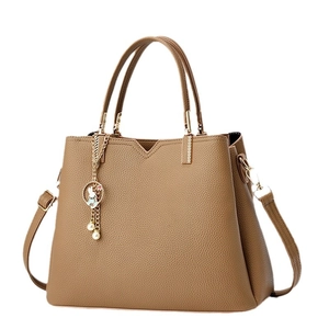 Litchi texture khaki handbag with V-cut design and cute rabbit pendant on white background