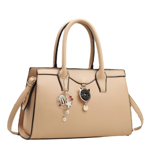 Sac à main élégant en cuir litchi abricot avec breloque chat et pendentifs sur fond blanc