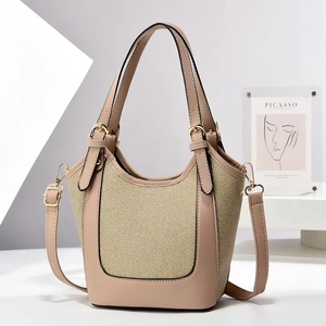 Detail of a beige leather bucket bag featuring woven panels and gold hardware accents