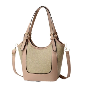 Minimalist beige woven bucket bag with nude leather trim and adjustable strap