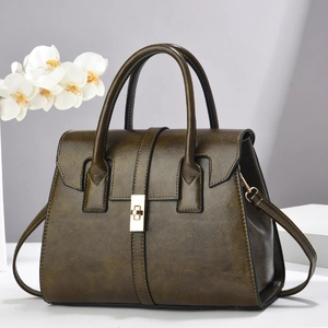 Détail d'un sac à main en cuir ciré vert olive avec fermoir rotatif en métal doré