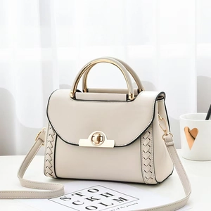 Détail du sac en cuir crème avec poignée dorée et texture tissée sur les côtés