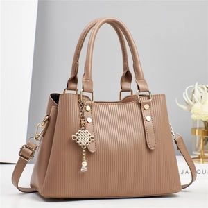 Détail du sac à main kaki à rayures avec pendentif doré et perle décorative