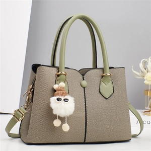 Elegant beige woven handbag with avocado green leather trim and plush ball charm detail