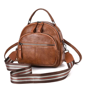 Detail of brown litchi grain leather backpack featuring a colorful striped woven strap