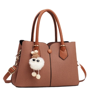 Brown woven texture handbag with dark leather straps and a cute plush charm