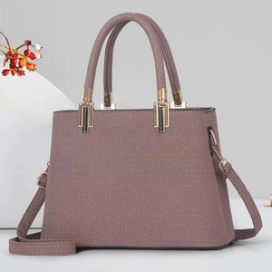 Detail of woven texture mauve tote bag with golden hardware and round handles