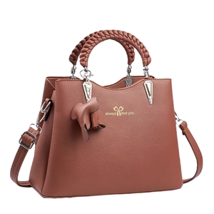 Caramel brown multi-layer handbag in lychee leather with woven handles and cat charm