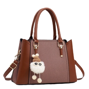 Sac à main marron avec texture tissée et un joli pendentif en peluche blanche