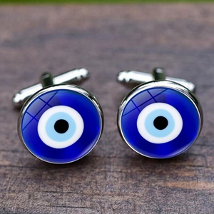 Λεπτομέρεια macro από ασημί μανικετόκουμπα Evil Eye σε σκούρα ξύλινη επιφάνεια