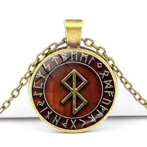 Close-up of bronze Viking Elder Futhark rune pendant with gold symbols on red background
