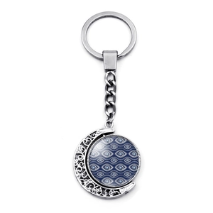 Detalle del llavero de luna giratoria plateado con dije de ojo turco azul de cristal