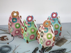 Detail of four colorful donut-themed pastry gift boxes with creative die-cut handles
