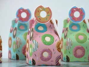 Three colorful pastry boxes with donut illustrations and unique die-cut donut handles