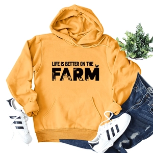 Flat lay of yellow 'Life is Better on the Farm' hoodie with tractor and wheat graphics