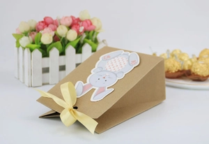 Detail of Easter kraft paper gift bag with yellow ribbon bow and cute bunny pattern
