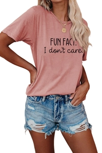 Detailed view of pink short sleeve tee with FUN FACT I don't care slogan and ripped denim