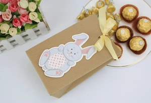 Close-up of Easter kraft paper gift box with cartoon bunny tag and yellow silk ribbon