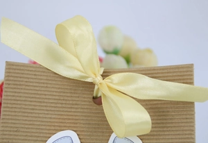 Detail of a brown kraft paper gift box with a soft yellow satin ribbon bow and bow tie