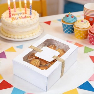 White cardboard cake box with wavy window and twine bow showing cookies inside