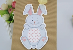 Detail of blue Easter bunny card with heart pattern tied to a kraft box with yellow ribbon
