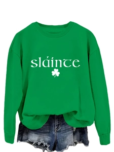 Détail du sweat vert Sláinte avec imprimé trèfle blanc et short en jean bleu