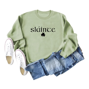 Vue à plat du sweat-shirt vert sauge avec texte sláinte et motif de trèfle