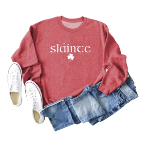 Détail du sweat-shirt rouge avec texte blanc Sláinte et motif de trèfle imprimé