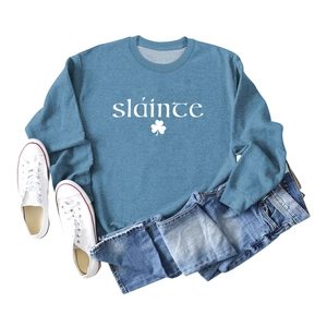 Mise à plat d'un sweat bleu avec texte Sláinte blanc et motif de trèfle imprimé