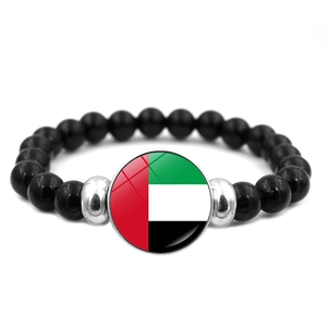 Macro detail of elastic beaded bracelet with UAE flag glass cabochon charm and black beads