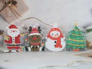 Gros plan de quatre boîtes cadeaux en PVC transparent avec motifs de Noël et poignées