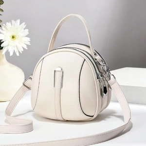 Minimalist beige round shoulder bag with three zip compartments and silver hardware