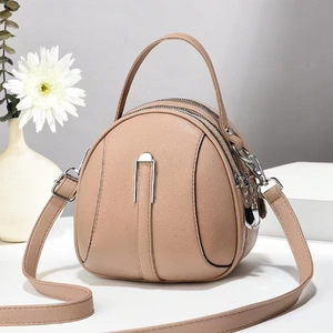 Detail of round beige crossbody bag featuring dual zippers and textured leather