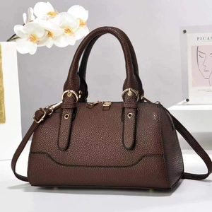 Close-up of deep brown litchi grain leather bag with golden hardware and handles
