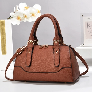 Close-up of brown litchi grain leather handbag with gold zippers and metal hardware details