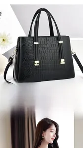 Détail du sac à main noir à texture crocodile avec garnitures dorées et bandoulière