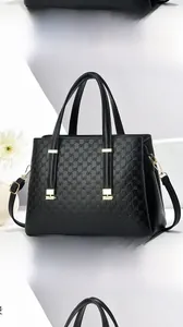 Détails d'un sac cabas noir avec texture de lettres gaufrées et finitions dorées
