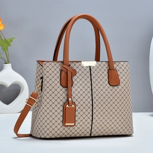 Elegant beige patterned tote bag with brown leather handles and adjustable shoulder strap