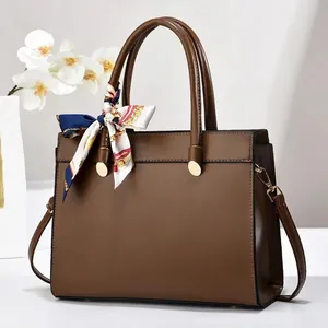 Détail du sac à main en cuir marron foncé avec foulard en soie et finitions dorées
