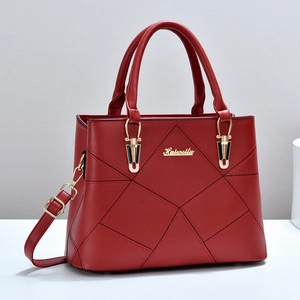 Détail d'un sac à main en cuir matelassé rouge avec logo en métal doré et coutures fines