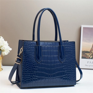 Detail of navy blue crocodile embossed glossy leather tote bag with sturdy handles