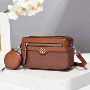 Close-up of brown patchwork shoulder bag with metal clover logo and mini coin purse detail
