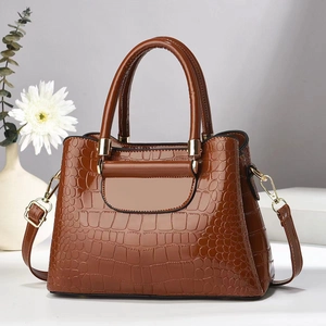 Detail of stone embossed pattern on brown faux leather handbag with gold hardware