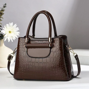 Dark brown faux crocodile skin handbag with top handle and gold hardware in elegant setting