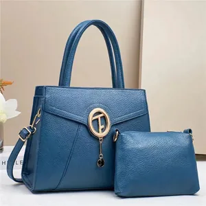 Detail view of navy blue lychee grain leather tote set with gold logo and tassel accent