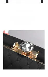 Close-up of heart embroidered handbag featuring a large crystal on gold metal base