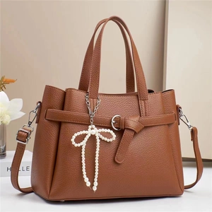 Detail of brown litchi pattern leather tote bag with pearl bow charm and strap