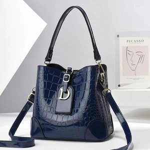 Detail of navy faux crocodile leather bucket bag featuring a metallic D-shaped charm