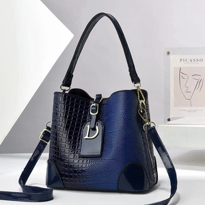 Detailed view of stone-textured gradient bucket bag with gold D-pendant and leather straps