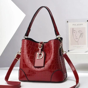 Detail of burgundy crocodile pattern bucket bag with golden D-ring and adjustable strap